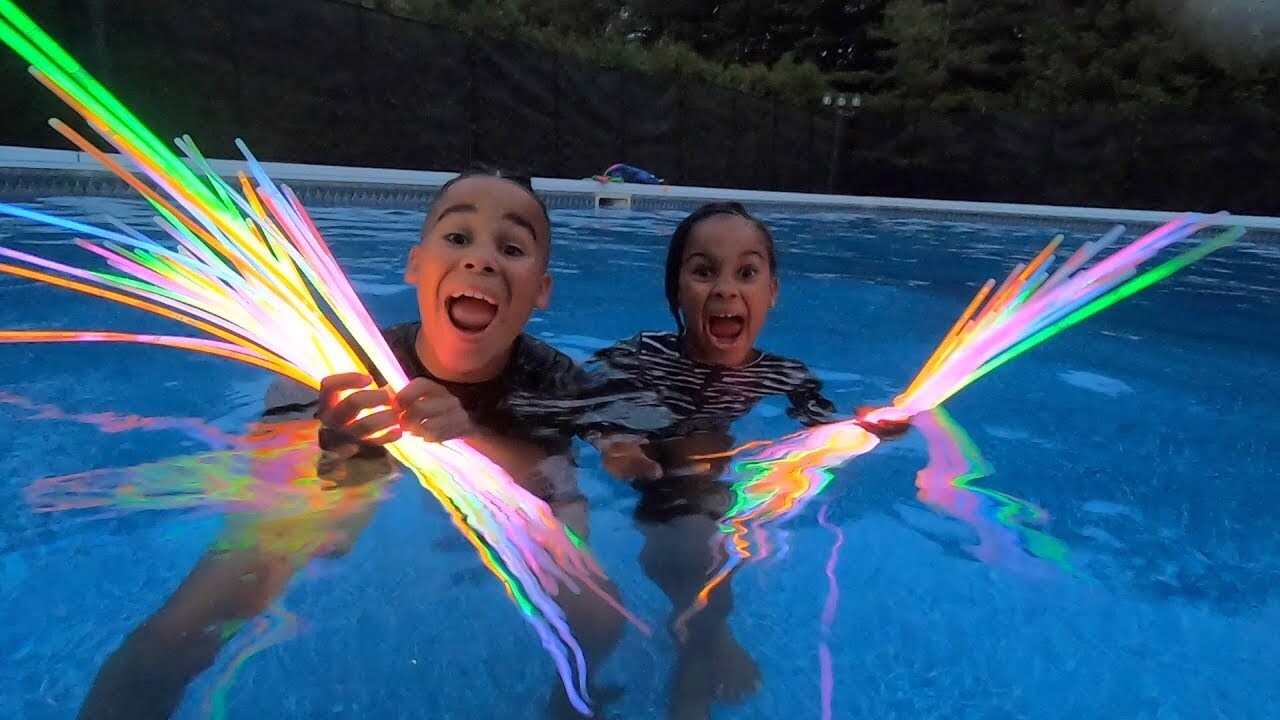 Kids holding glow sticks in a pool